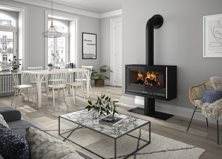 ORANIER Holzkaminofen Ziva XL Stahl Schwarz auf Standfuß in einer Wohnung im Landhausstil. Weißer schlichter Esstisch links.