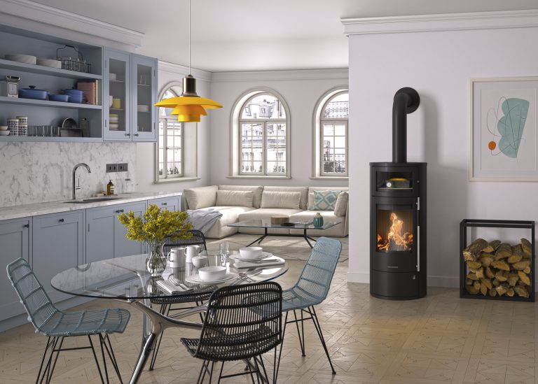 Wohn-Essbereich mit Kaminofen. Küche im Hintergrund im Landhausstil mit Glastisch und Stühlen. Backraum im Kaminofen.