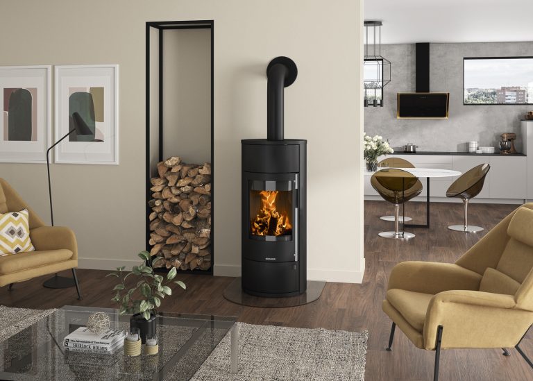 Eleganter Wassergeführter Kaminofen in Wohnzimmer. Modische Küche mit tisch und außergewöhnlichen Stühlen im Hintergrund.