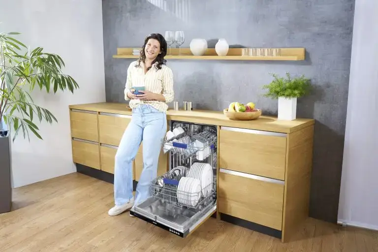 Eine junge Frau, die neben einem ORANIER GSV360-Geschirrspüler steht, mit einer Tasse Kaffee in der Hand.