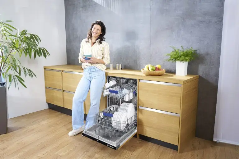Eine junge Frau, die neben einem ORANIER GSV360-Geschirrspüler steht, mit einer Tasse Kaffee in der Hand.