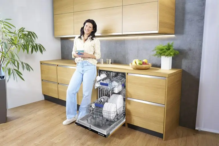Eine junge Frau, die neben einem ORANIER GSV360-Geschirrspüler steht, mit einer Tasse Kaffee in der Hand.
