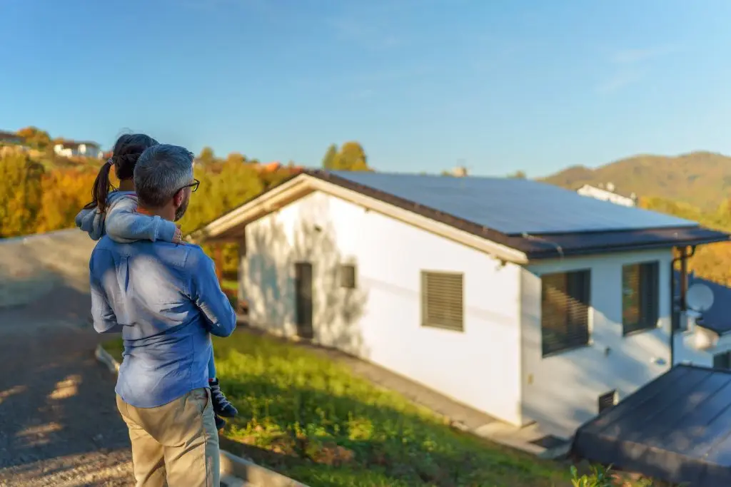 Vater und Tochter stehen vor ihrem Haus mit Solaranlage