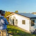Vater und Tochter stehen vor ihrem Haus mit Solaranlage