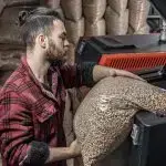 Mann lädt Pellets in einen Biomassekessel