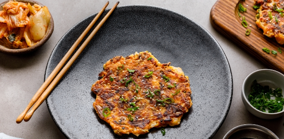 Auf dem Bild sieht man eine Koreanische Pfannkuchen mit Kimchi auf grauen Geschirrangerichtet
