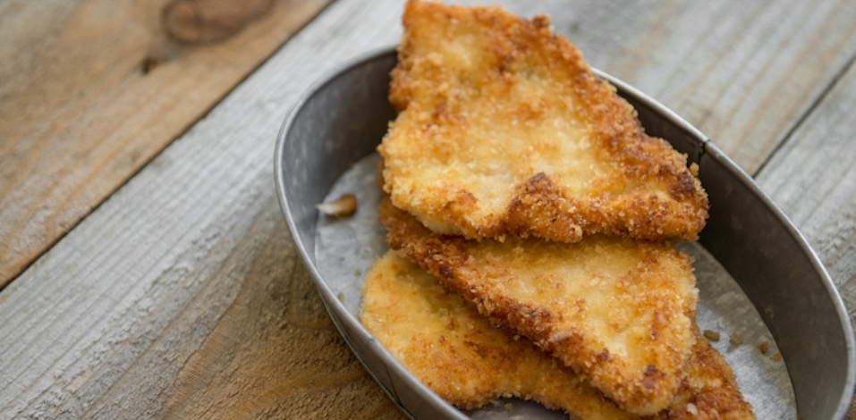 Das Bild zeigt eine grauen Behälter mit Hähnchenschnitzel drin