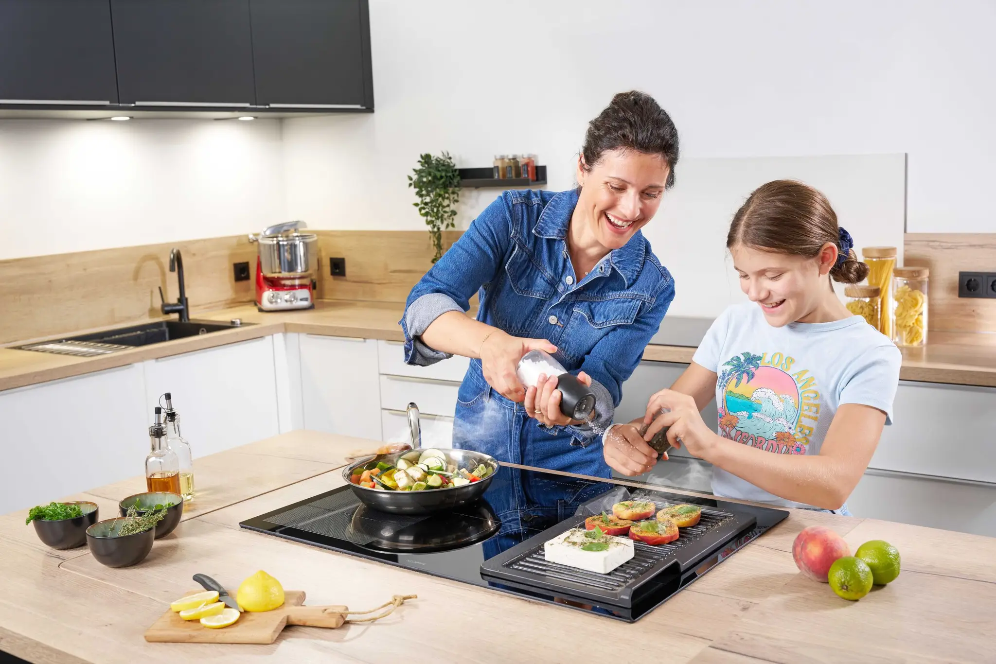 Mutter und Tochter stehen in der Küche vo dem ORANIER Induktionskochfeld FLI580 und kochen gemeinsam